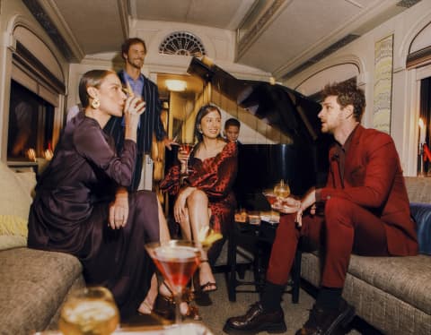 Guests drinking cocktails and smiling happily at the Piano Bar Car