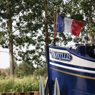 The nose of the blue and white Amaryllis barge, flying the French flag on its serene journey along the Burgundy waterways.