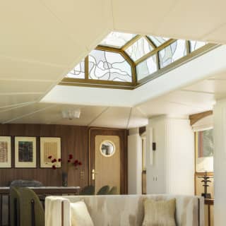 A grey high-sided sofa and green marble table sit in the light of the glass ceiling lantern in the simply elegant lounge.