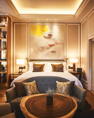 An original Ele Pack abstract painting hangs above the kingsize bed, echoing the warm tones of the hardwood floor and table
