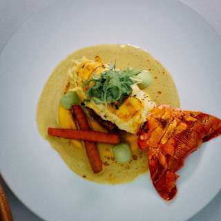 A gourmet dish of grilled local crayfish served in a lemon salmoriglio sauce with roasted carrots and rocket leaves.