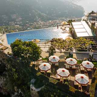 Six parasols offer shade to sun-loungers on a deck behind the pool which drops off into sublime coast views, seen from above.