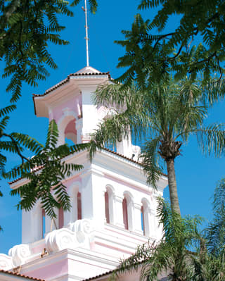 The immaculately restored Hotel das Cataratas colonial-style bell tower between mature palm trees and cloudless blue sky