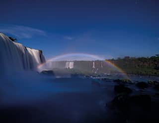 An evening rainbow caused by moonlight in the spray above the cascades of Iguassu Falls