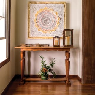 Close-up of candles and plants on a side-table under an abstract painting