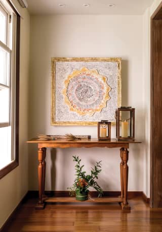 Close-up of candles and plants on a side-table under an abstract painting>