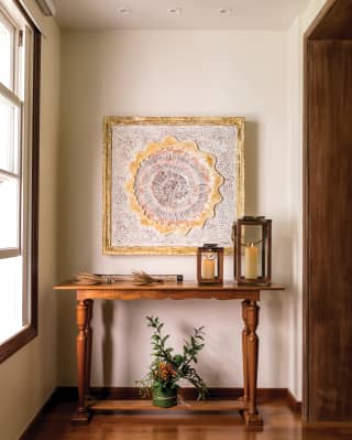 Close-up of candles and plants on a side-table under an abstract painting