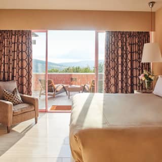 Sliding doors from a room of warm ochres and Tuscan yellow open out onto a furnished balcony with views of lush Tuscan hills