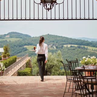 Waitress strolling across a restaurant terrace with forest covered hills beyond