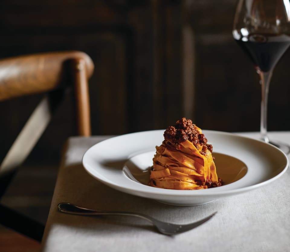 Close-up of a linguine and beef ragu dish in a white circular bowl