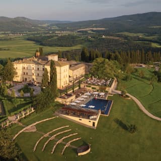 Behind the steps of an ancient Etruscan amphitheatre, the pale yellow walls of the hotel stand tall amid extensive gardens