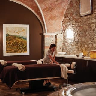 Spa therapist preparing a massage table in a lamplit, vaulted spa area