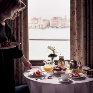 In-room dining table laden with breakfast dishes overlooking St Mark's Square