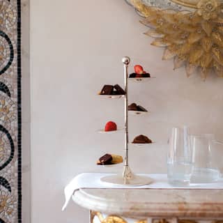 Six-tiered cake stand laden with sweet treats on a room service tray