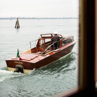 Classic Venetian water taxi sailing into the distance at sunset