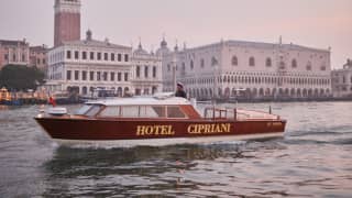 Venetian water taxi emblazoned with 'Hotel Cipriani' sailing by St Mark's square