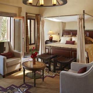 King-size four-poster bed in a bright hotel room in Spanish-colonial style