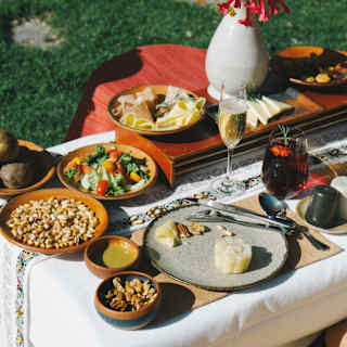 Looking down on plates of nuts, salad, cheese and vegetables served at a low table in the gardens, seen close up.