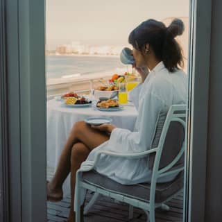 Lady relaxing with breakfast on a balcony overlooking Copacabana beach
