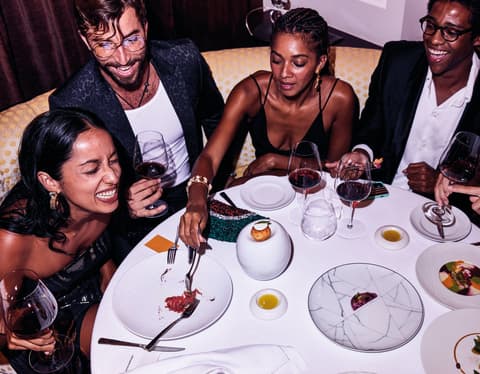 A group of friends dining, drinking and laughing around the table