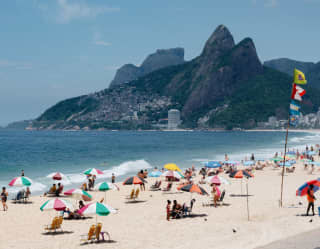Lifeguard flags fly high on Copacabana Beach. Colourful parasols dot the sand near the patterned black and white boardwalk