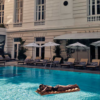 A woman in a black swimsuit resting on an airbed in the pool at the Copacabana Palace