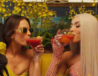 Supermodel Alessandra Ambrosio and drag queen Pabllo Vittar wear vibrant yellow and pink as they sip fruit cocktails