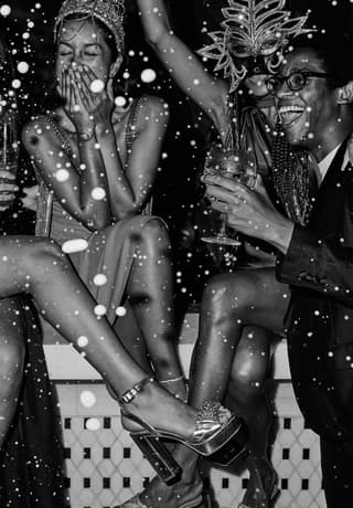 Black and white shot of a group of friends laughing, drinking and celebrating