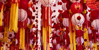 Paper lanterns, origami cranes and baubles hang with streamers of yellow and red in a forest of party ceiling decoration