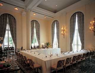 Meeting tables are set in a horseshoe shape with individual water and notepads. Cathedral height arched windows add drama