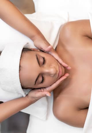 Birds-eye-view of a lady on a massage table enjoying a facial spa treatment>