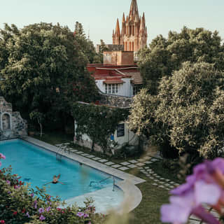 Outdoor pool in a garden courtyard with stepping stone pathways surrounded by floral shrubs and trees