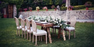 Outdoor banquet table in a garden with a full-length lily centrepiece