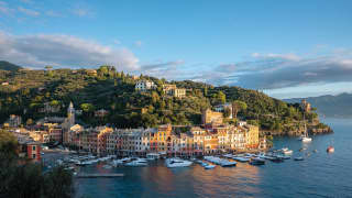 Curved row of sherbert coloured town houses lining a tranquil harbour at sunset