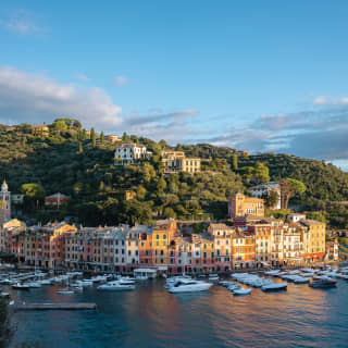 Curved row of sherbert coloured town houses lining a tranquil harbour at sunset