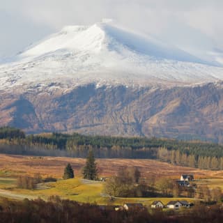 The mountain of Aonach Mor, linked by a mountain pass to Aonach Beag, rises from the glen, gathering snow as it ascends.