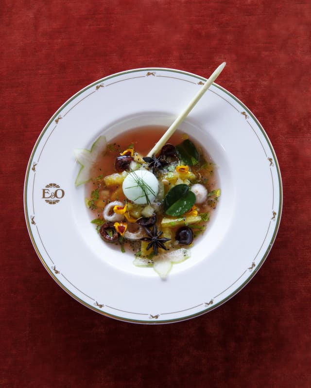 Chef Andre Chian's “nine peppers jus” herby sixteen-hour-braised beef cheek, served in a white bowl on a red tablecloth.​⁣