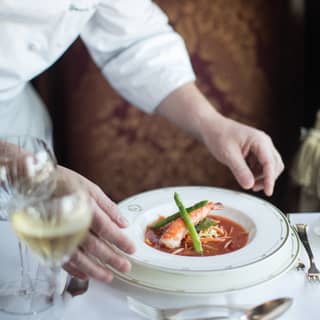 Close-up of a white gold-tipped bowl containing a red lobster soup
