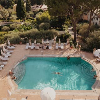 Some guests dangle their feet and others swim in the turquoise lozenge of a lovely pool. Stone pines offer dappled shade