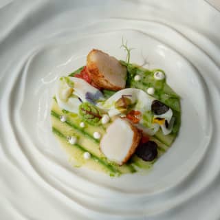 Seared scallops served on asparagus strips with garnish create a garden in the centre of one of Otto Geleng's unique plates.