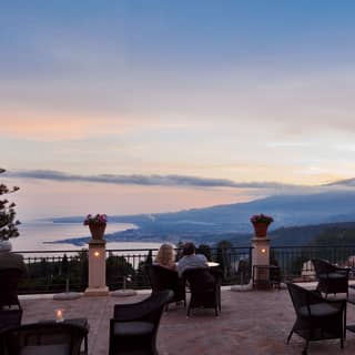 Two couples absorb the views of Taormina's coast and contours from the terrace, where candles add magic to the dusk light.