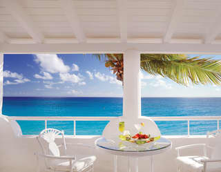 Balcony breakfast table under blue sky with Caribbean sea views
