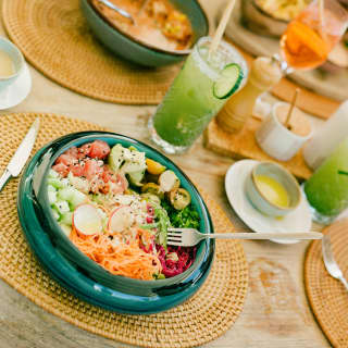 Angled image over a lunch at Laplaj, with a bright salad of chopped and shredded vegetables, and a cucumber-garnished drink.