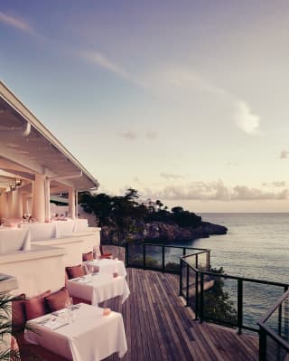 Clifftop restaurant terrace overlooking the Caribbean sea at sunset
