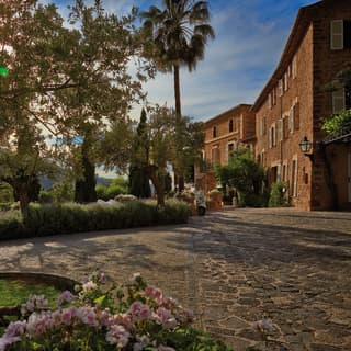 A low sun throws long shadows from tall olives, palms and pines. The hotel's stone walls glow a reddish gold and feel peaceful