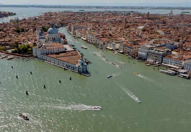 Easterly aerial view of sunny Venice, showing Giudecca and the centre, divided by the Grand Canal, and surrounding lagoon.