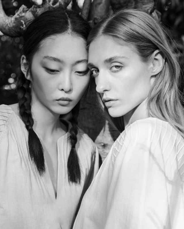 In black and white, two models pose in Yolanda tops, with split crewnecks and "Charro" braiding detail, by Collectiva Concepción.