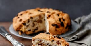 A slice of a Ligurian fruit cake with the remaining cake on a plate behind