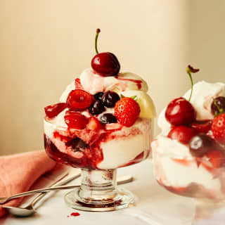 Close-up of two glass bowls of Paciugo, made with layers of gelato, whipped cream, summer berries and Amarena cherries.