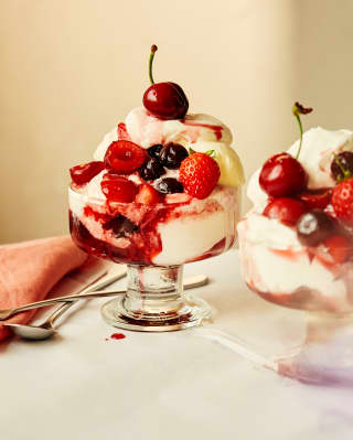 Close-up of two glass bowls of Paciugo, made with layers of gelato, whipped cream, summer berries and Amarena cherries.